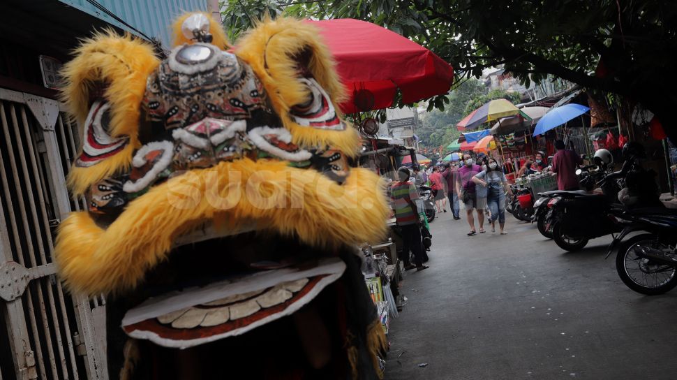 Pengamen mengenakan kostum barongsai mencari nafkah di Pasar Petak Sembilan, Glodok, Jakarta, Senin (16/5/2022). [Suara.com/Angga Budhiyanto]
