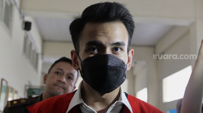 Terdakwa kasus pelanggaran Undang-Undang (UU) ITE Adam Deni berjalan menuju ruang sidang di Pengadilan Negeri Jakarta Pusat, Selasa (7/6/2022). [Generalvekalat.org/Angga Budhiyanto]